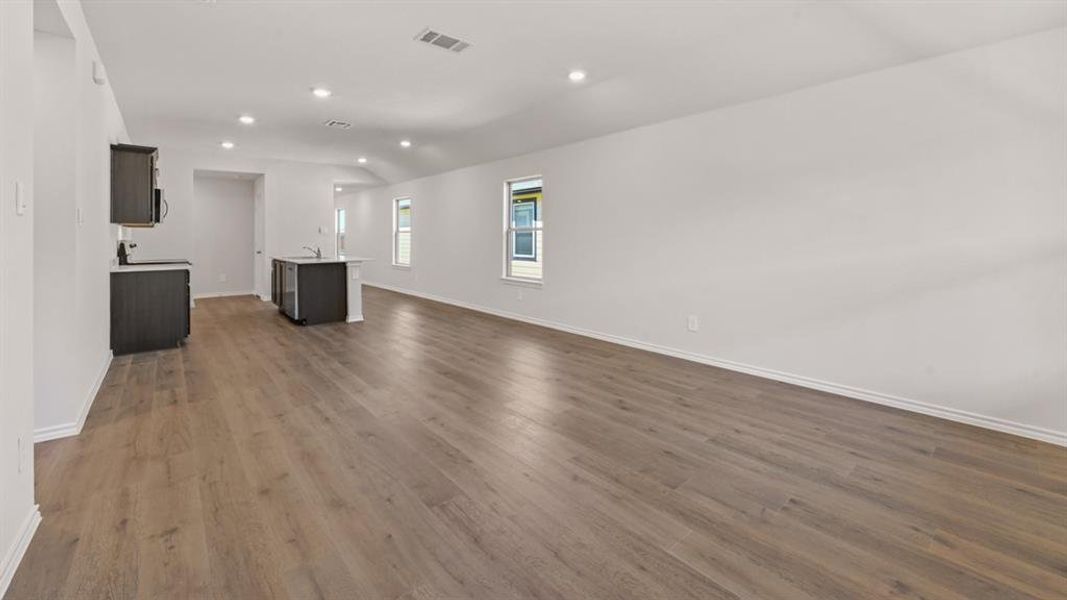 Open-concept living area featuring wood-finish flooring, recessed lighting, and multiple windows