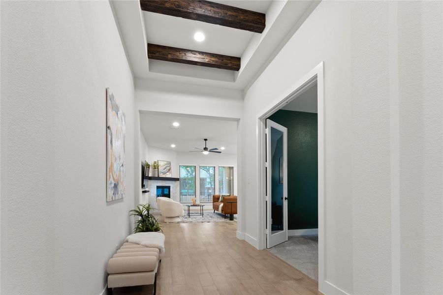 Hallway featuring light wood-finish flooring, a tray ceiling with exposed wood beams, and recessed lighting