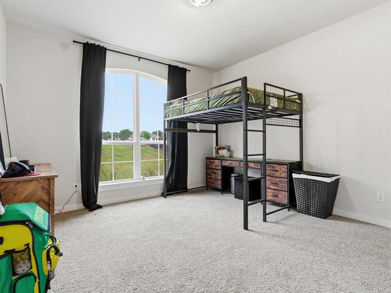 Comfortable secondary bedroom faces the street, with natural light and ample closet space.