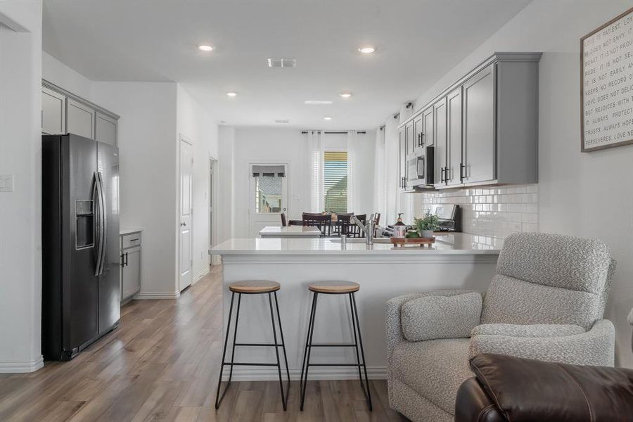 Kitchen with gray cabinetry, decorative backsplash, kitchen peninsula, and appliances with stainless steel finishes