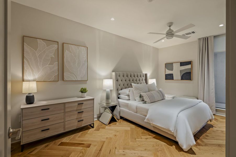 Herringbone hardwood floors create an inviting and elegant ambiance in this naturally illuminated bedroom.