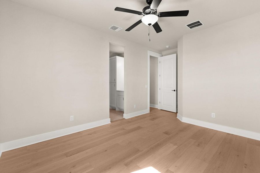 Unfurnished bedroom featuring light wood-type flooring, a ceiling fan, and connected bathroom