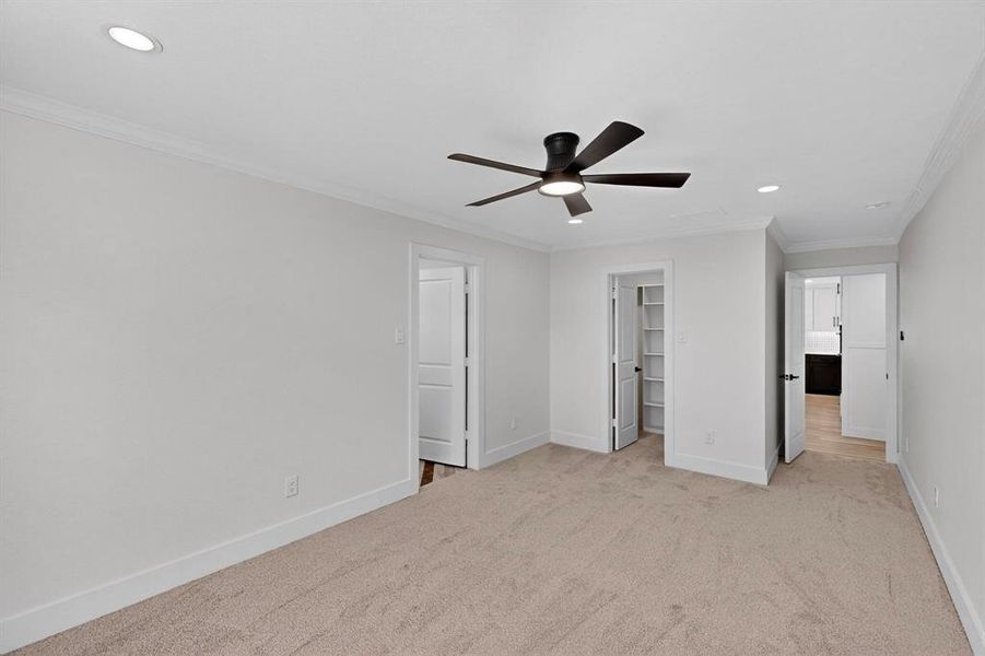 Unfurnished bedroom featuring a spacious closet, crown molding, light colored carpet, recessed lighting, and a ceiling fan