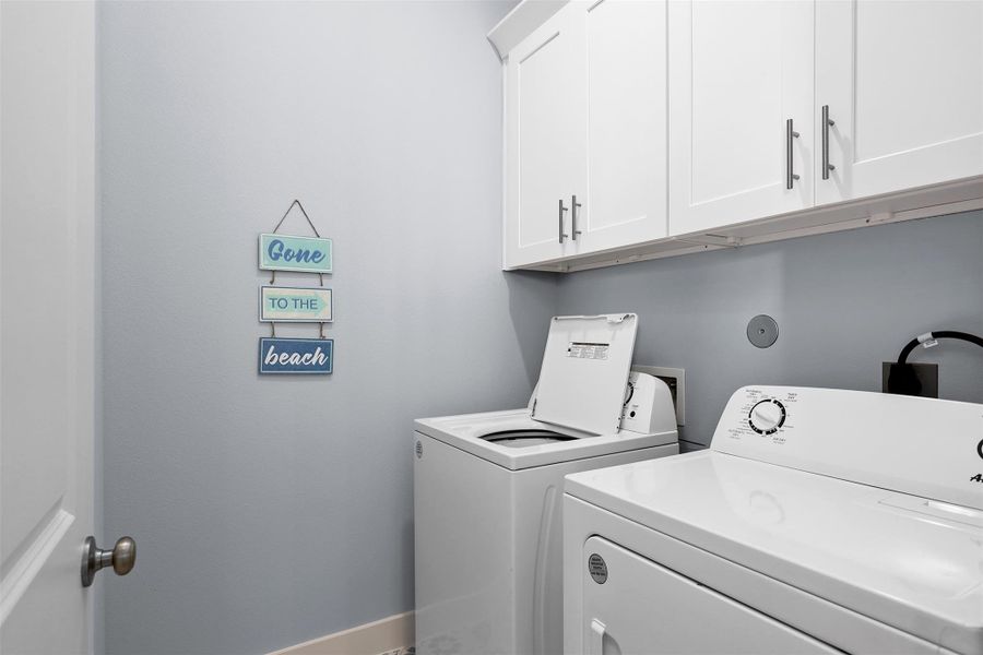 The laundry room is thoughtfully designed with built-in cabinetry, ample storage, and full-size washer and dryer connections to simplify household tasks.
