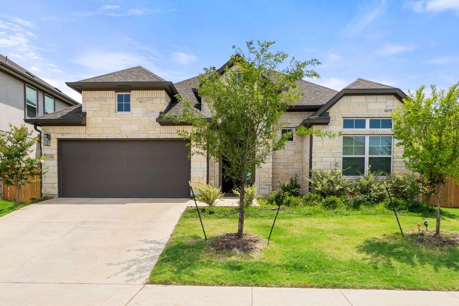 French country style house featuring stone siding, a shingled roof, and concrete driveway French country style house featuring stone siding, a shingled roof, and concrete driveway