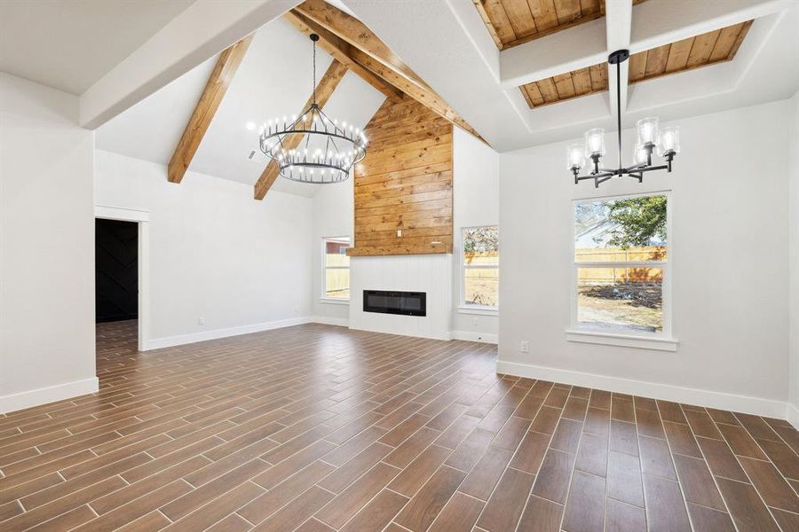 Unfurnished living room featuring beamed ceiling, high vaulted ceiling, wooden ceiling, and an inviting chandelier