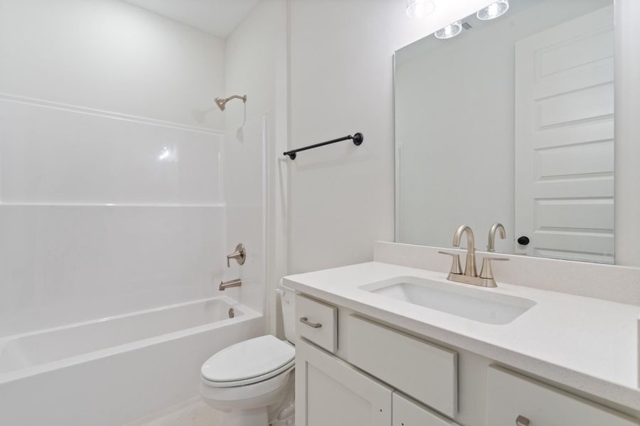 Integrated bathtub with shower, white vanity with an undermount sink, solid surface countertop, and brushed nickel fixtures Integrated bathtub with shower, white vanity with an undermount sink, solid surface countertop, and brushed nickel fixtures