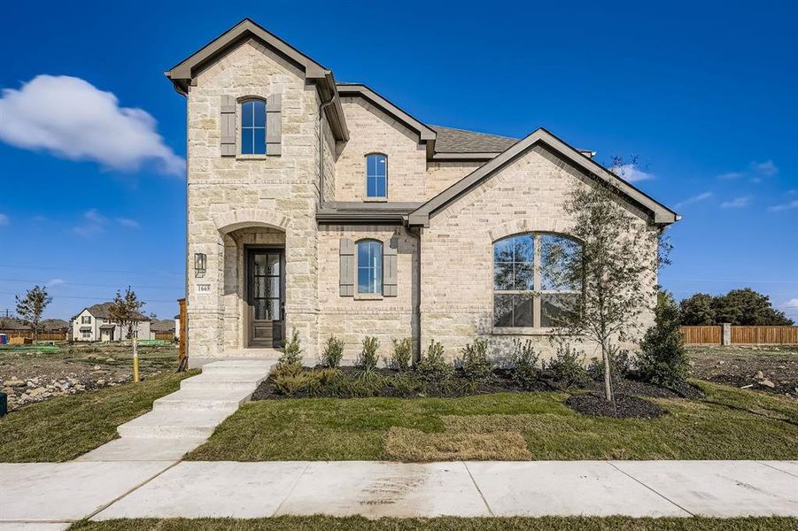 French country style house with stone siding, brick siding, and a shingled roof
