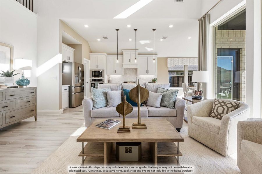 Open-concept living room with gray sofa, wood coffee table, and kitchen visible in background with white cabinets and stainless appliances. Open-concept living room with gray sofa, wood coffee table, and kitchen visible in background with white cabinets and stainless appliances.