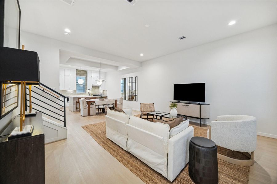 Open-concept living and dining area offers seamless flow and abundant natural light. Clean lines, neutral tones, and light wood floors create a bright, modern atmosphere that connects effortlessly to the kitchen for relaxed entertaining.