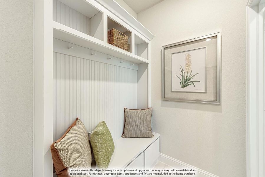 Mudroom nook with white built-in bench, upper shelves, coat hooks, and beadboard wall paneling