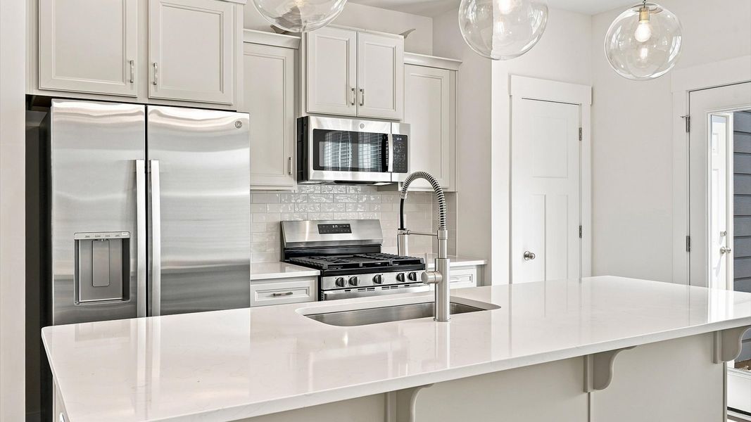 Tasteful kitchen with a streamlined island and modern finishes in a first-class DRB Homes design Tasteful kitchen with a streamlined island and modern finishes in a first-class DRB Homes design