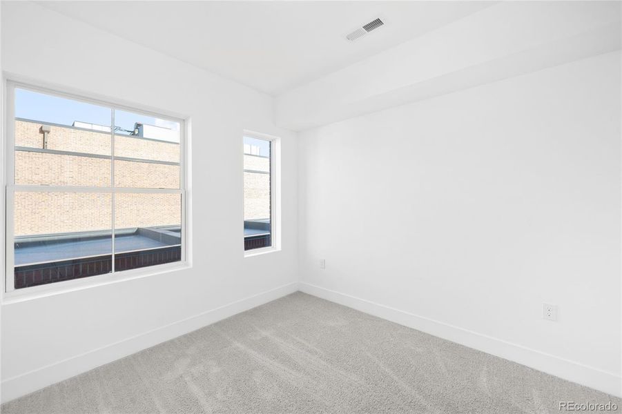 Expansive windows fill the second bedroom with natural light, creating a bright and comfortable retreat.