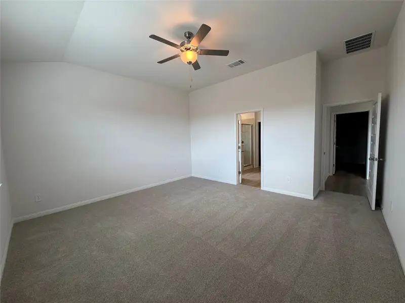 Unfurnished bedroom with light carpet, a ceiling fan, lofted ceiling, and ensuite bathroom