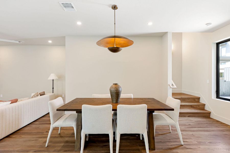 Dining area with light wood-style floors, recessed lighting, and stairs