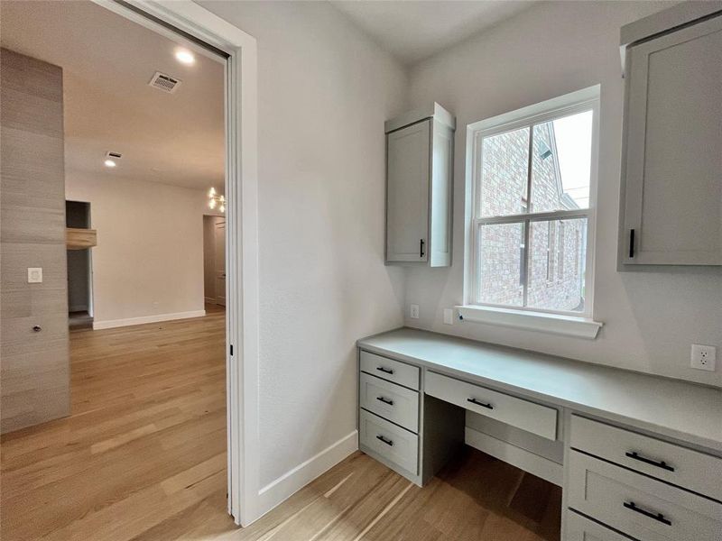 Home office featuring light wood-type flooring and built in desk