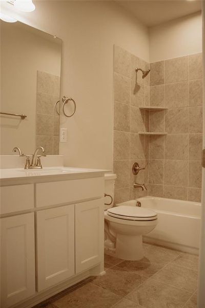 Full bathroom featuring vanity, tiled shower / bath combo, toilet, and tile patterned flooring