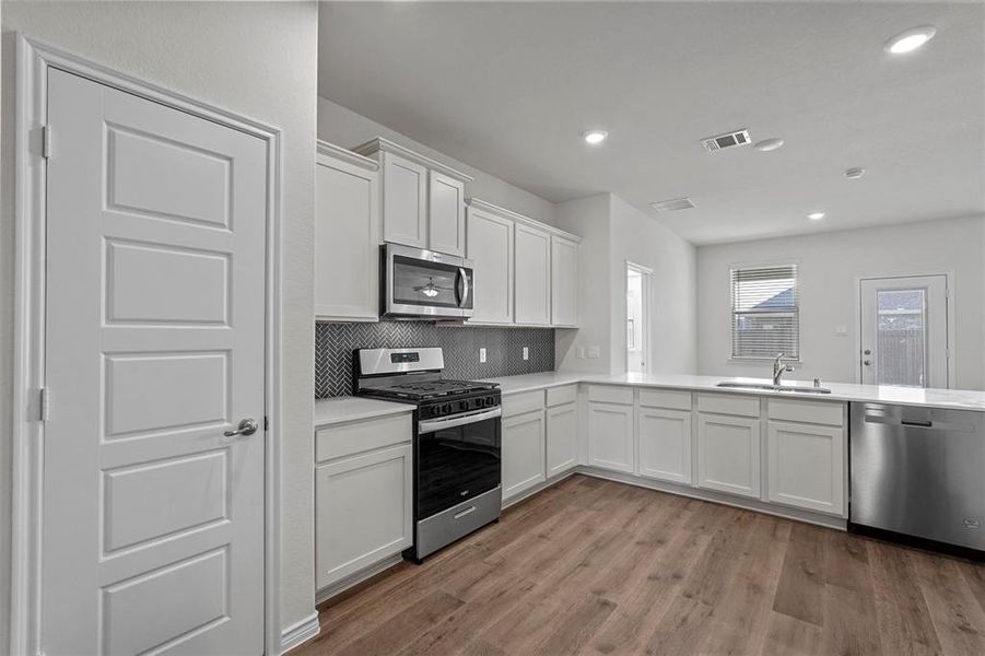 Kitchen featuring light hardwood / wood-style floors, stainless steel appliances, sink, and white cabinets