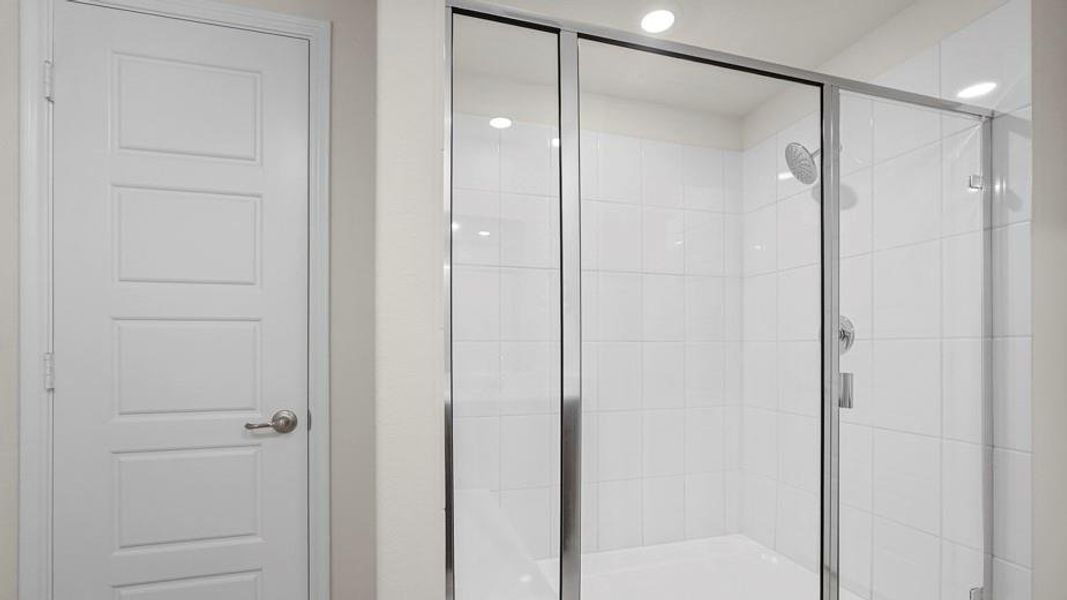 Modern shower enclosure with clear glass doors and white tiled walls