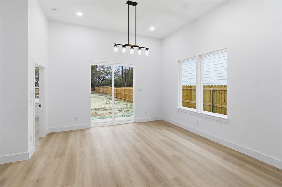 Unfurnished dining area with light wood-style floors, a high ceiling, and recessed lighting