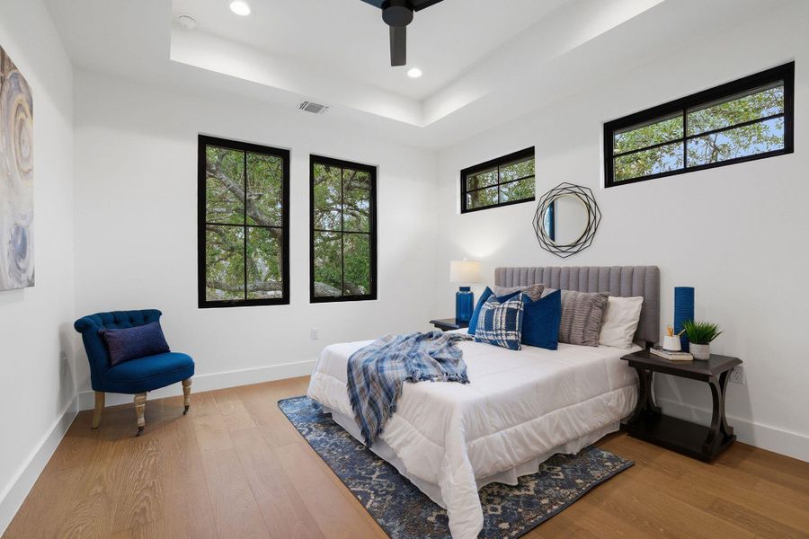 Bedroom featuring a raised ceiling, wood finished floors, ceiling fan, and recessed lighting