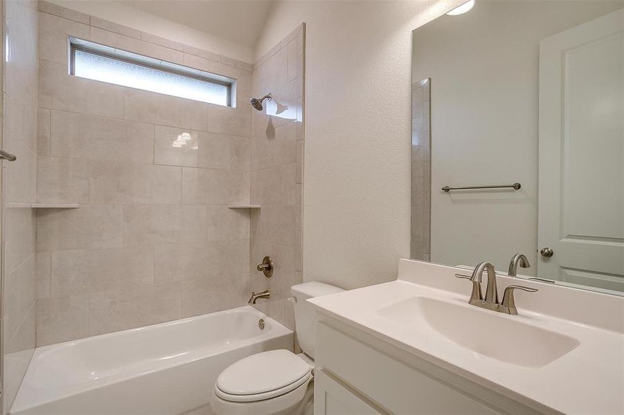 Full bathroom featuring vanity, tiled shower / bath combo, and toilet