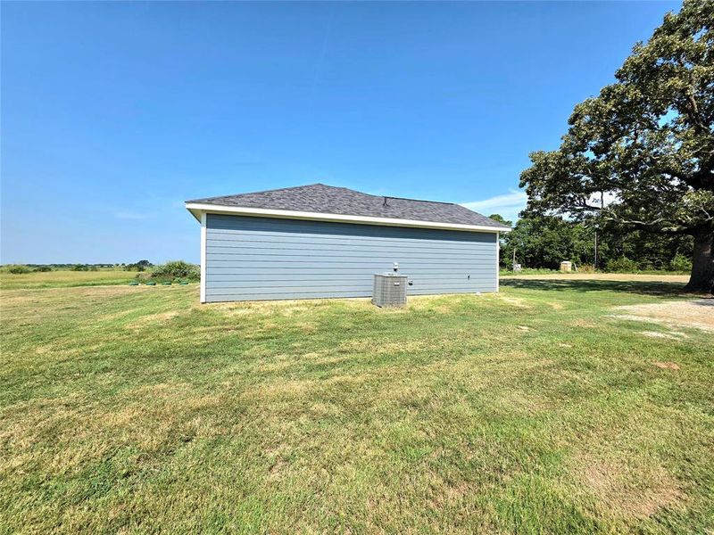 View of property exterior with a lawn and a shingled roof
