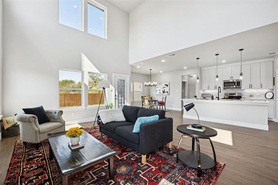 Living room featuring dark wood-type flooring, a high ceiling, a chandelier, and recessed lighting