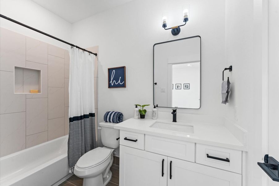 his well-appointed secondary bathroom features a classic tub and shower combo, ideal for both quick rinses and leisurely soaks