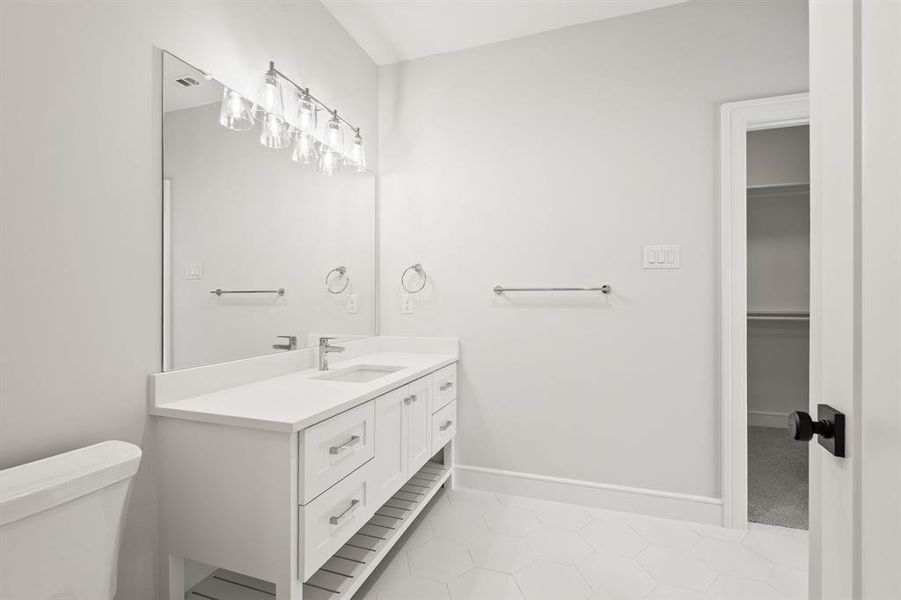 Bathroom with vanity, light tile patterned floors, and a walk in closet Bathroom with vanity, light tile patterned floors, and a walk in closet
