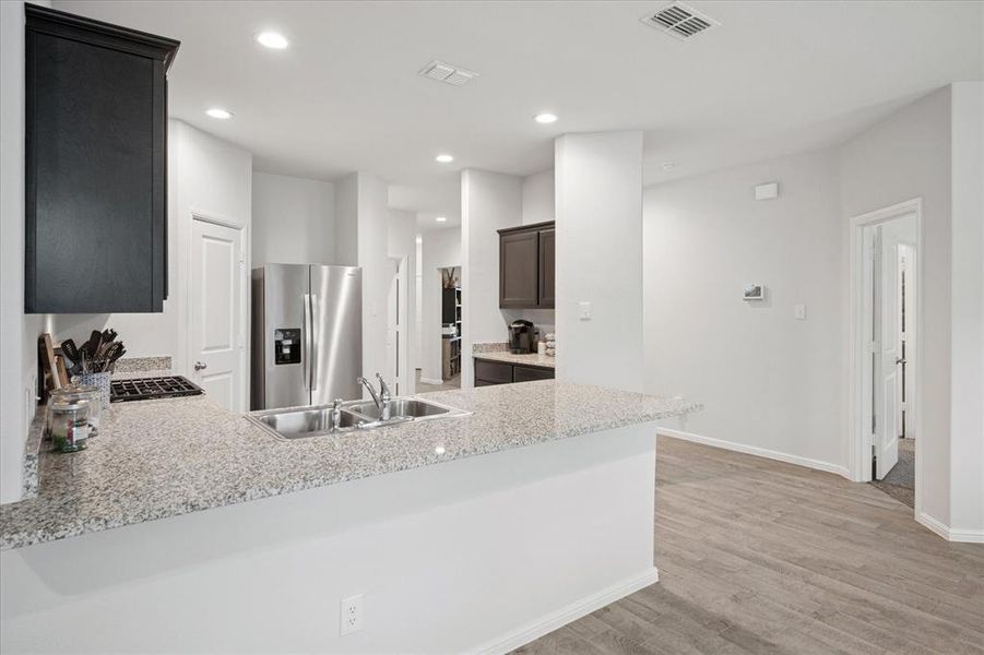 Kitchen featuring light wood finished floors, a peninsula, recessed lighting, and range with gas cooktop. Kitchen featuring light wood finished floors, a peninsula, recessed lighting, and range with gas cooktop.