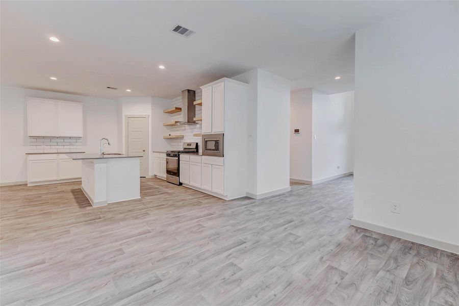 A true showpiece, the kitchen features quartz countertops, subway tile backsplash, floating wood shelves, and stainless appliances, all open to the expansive living area with luxury vinyl plank flooring. Ideal for hosting or relaxing, this bright and airy space defines modern comfort and functionality. A true showpiece, the kitchen features quartz countertops, subway tile backsplash, floating wood shelves, and stainless appliances, all open to the expansive living area with luxury vinyl plank flooring. Ideal for hosting or relaxing, this bright and airy space defines modern comfort and functionality.