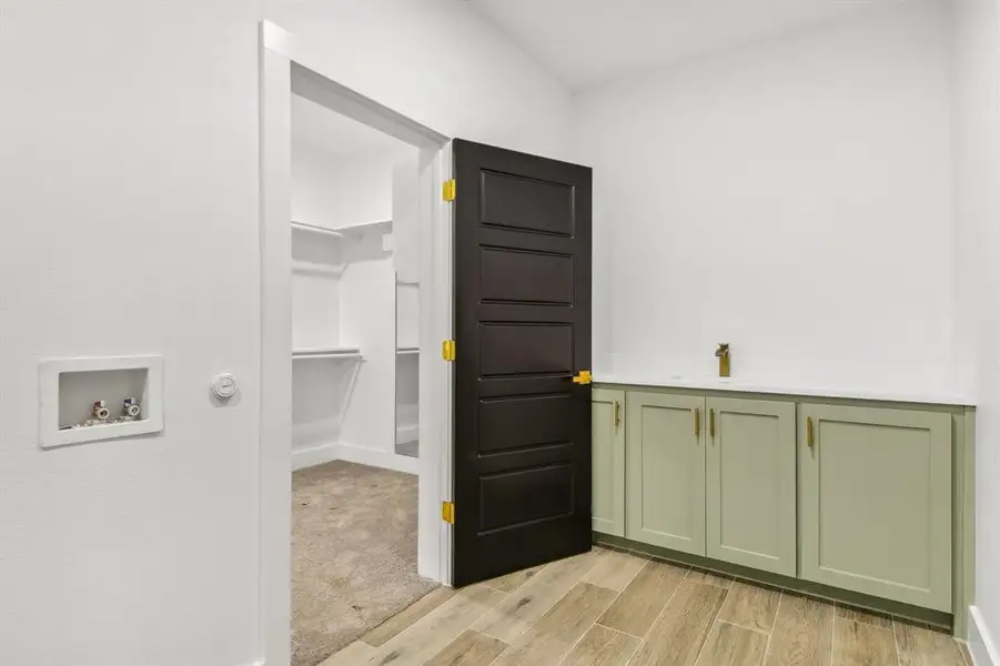 Washroom with wood finish floors and hookup for a washing machine Washroom with wood finish floors and hookup for a washing machine