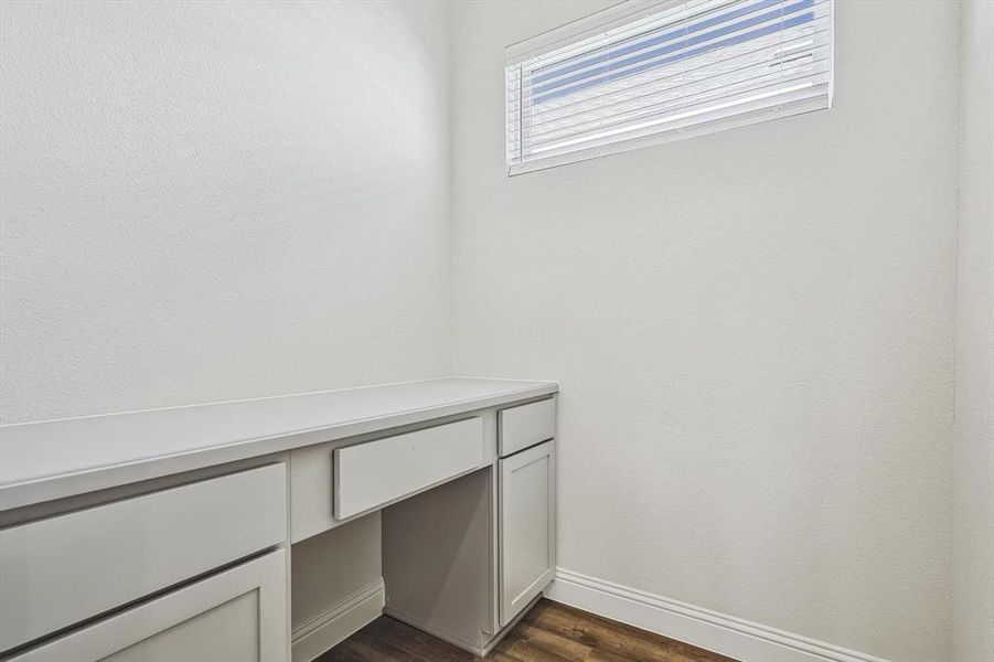 Unfurnished office featuring built in desk and dark wood-type flooring