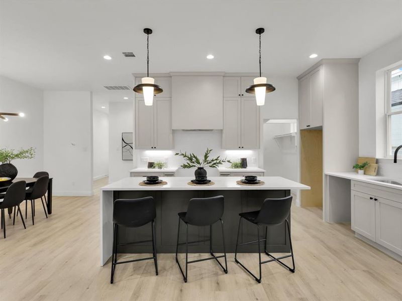 Kitchen with sink, a center island, pendant lighting, and light wood-type flooring