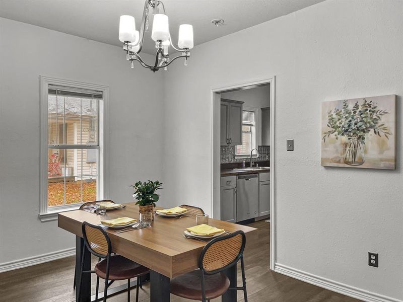 Dining room with a healthy amount of sunlight, dark wood-style floors. Seller may replace chandelier with ceiling fan