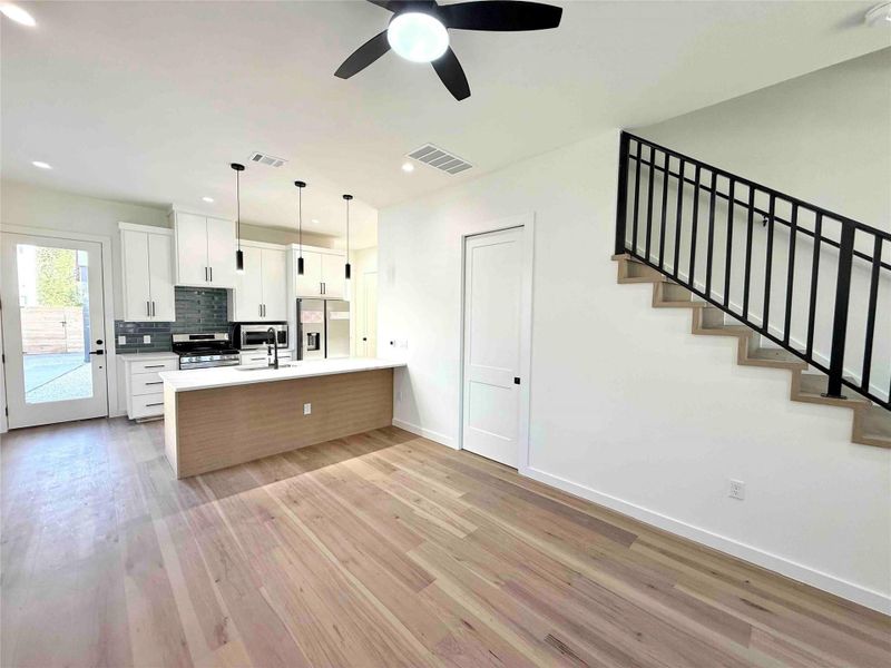 Kitchen featuring white cabinetry, a peninsula, stainless steel appliances, decorative light fixtures, and decorative backsplash