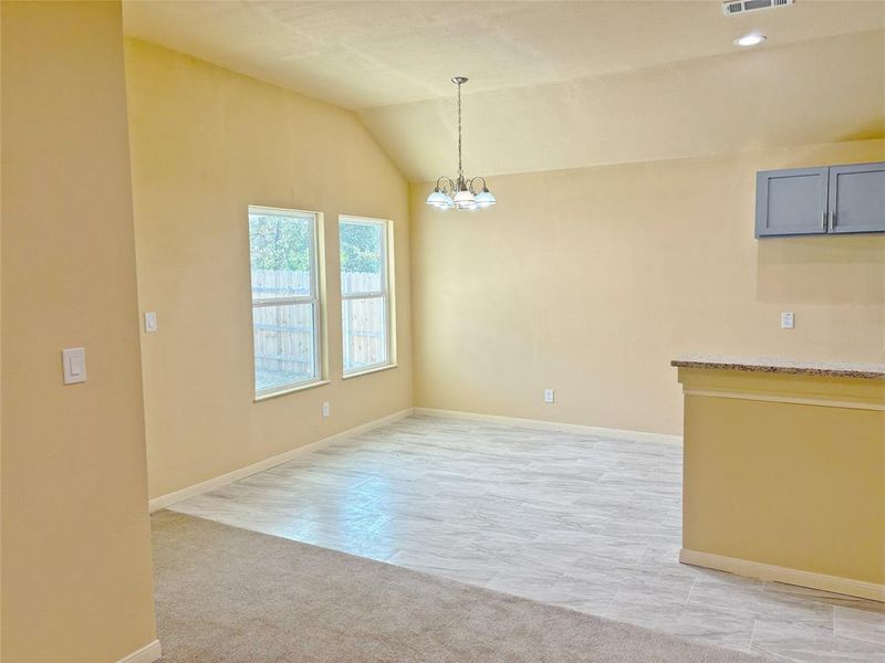 Unfurnished dining area with vaulted ceiling, a chandelier, and light colored carpet