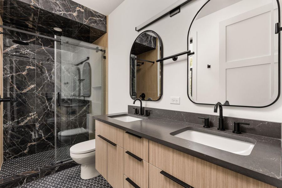Full bathroom featuring a marble finish shower, double vanity, and tile patterned floors Full bathroom featuring a marble finish shower, double vanity, and tile patterned floors