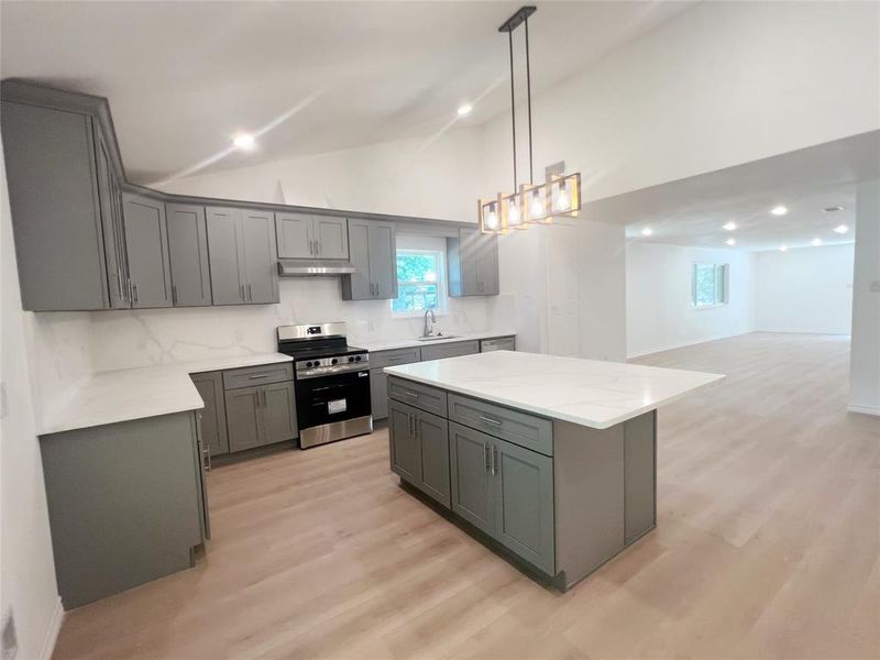Modern kitchen featuring grey shaker-style cabinetry and a central island with a white countertop