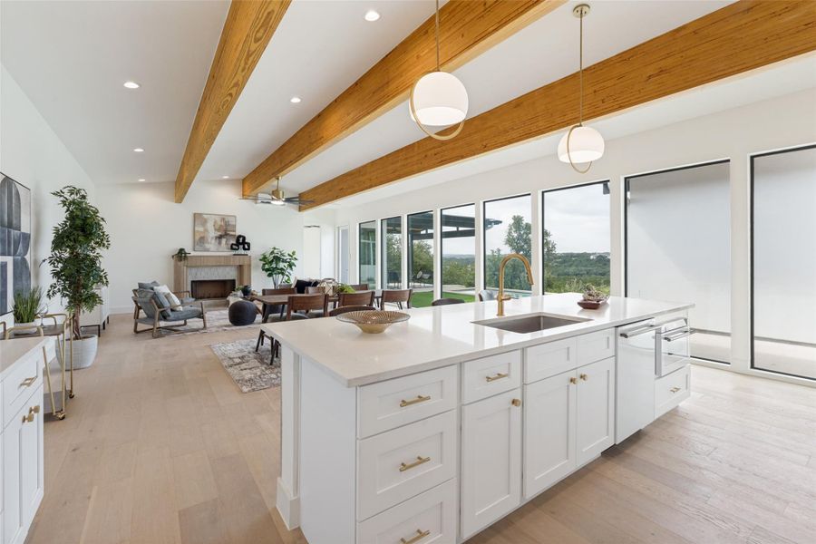 Exposed wood beams add architectural interest to this bright kitchen, complete with a generous island and modern fixtures.