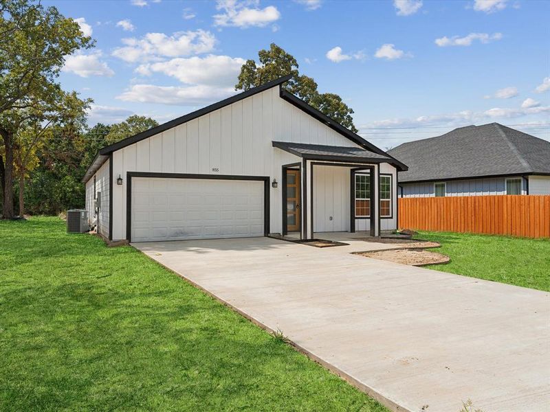 View of front of home featuring central AC unit, a garage, and a front lawn