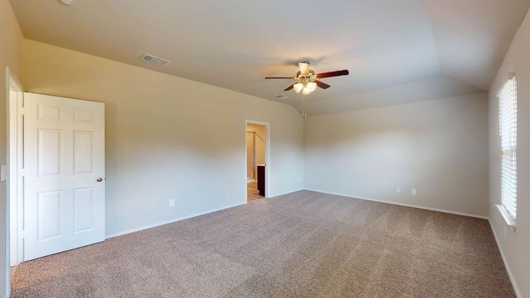 Spare room with carpet floors, a ceiling fan, and vaulted ceiling