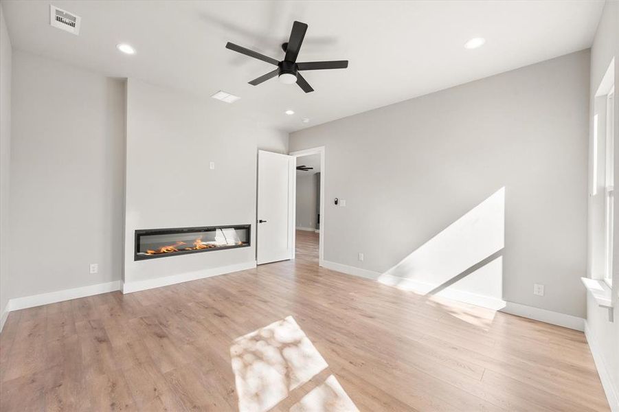Unfurnished living room with a glass covered fireplace, recessed lighting, light wood finished floors, and a ceiling fan Unfurnished living room with a glass covered fireplace, recessed lighting, light wood finished floors, and a ceiling fan