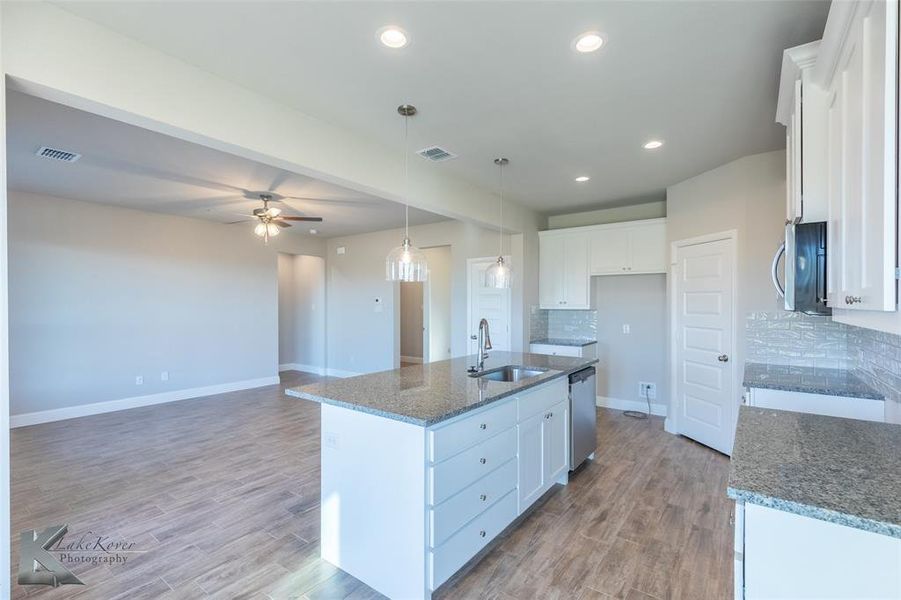 Kitchen with dark stone countertops, white cabinetry, wood finished floors, a ceiling fan, and recessed lighting