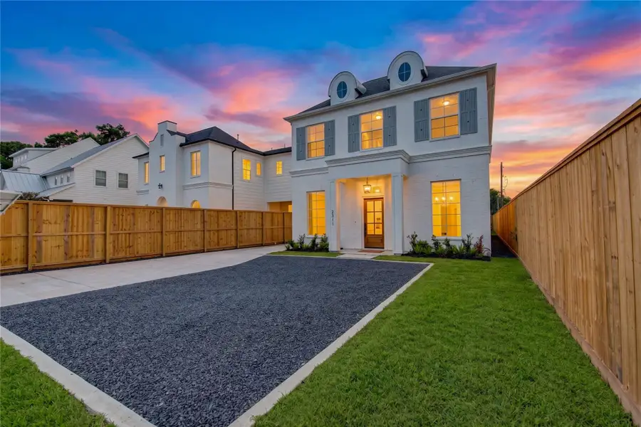 Striking dusk view of the front elevation showcasing the home’s modern architectural lines and warm exterior lighting against a dramatic sunset. The expansive gated motor court provides abundant private parking, while the illuminated façade creates an impressive sense of arrival. Striking dusk view of the front elevation showcasing the home’s modern architectural lines and warm exterior lighting against a dramatic sunset. The expansive gated motor court provides abundant private parking, while the illuminated façade creates an impressive sense of arrival.