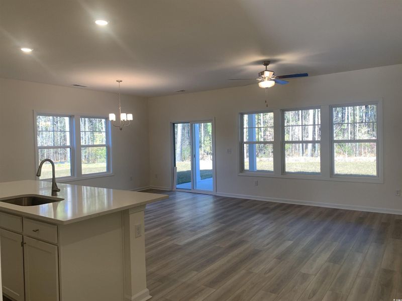Kitchen with dark wood-style floors, open floor plan, pendant lighting, white cabinetry, and a ceiling fan