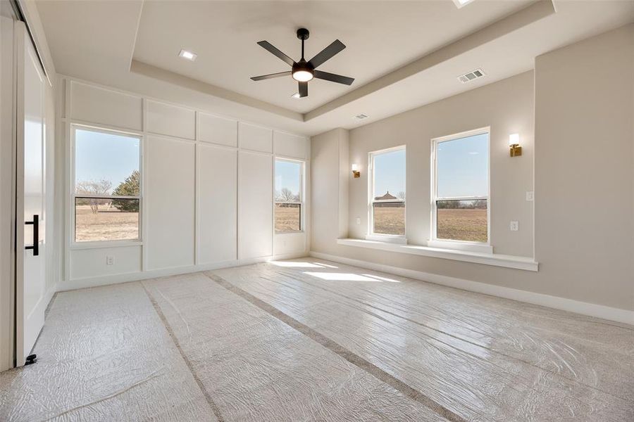 Unfurnished bedroom featuring a tray ceiling and a ceiling fan