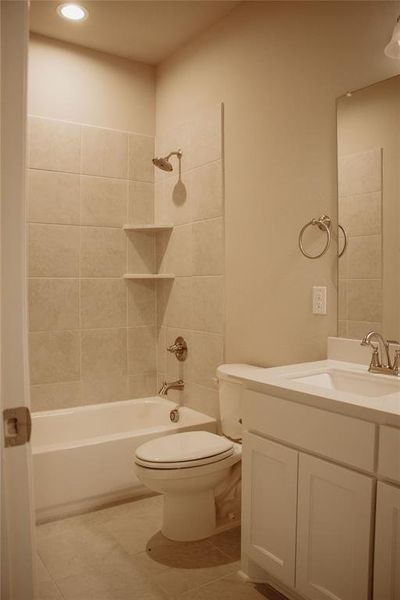 Full bathroom featuring tiled shower / bath, vanity, toilet, and tile patterned flooring