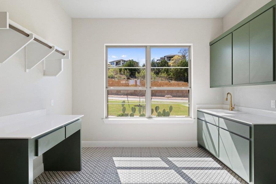 The spacious laundry room is equipped with cabinetry, a sink, folding space, and a desk.